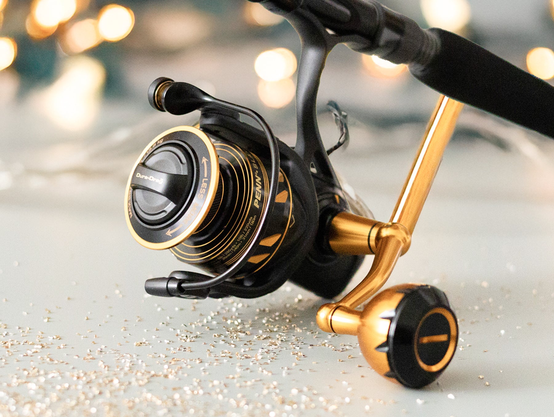 Fishing reel with gold and black finish on a reflective surface