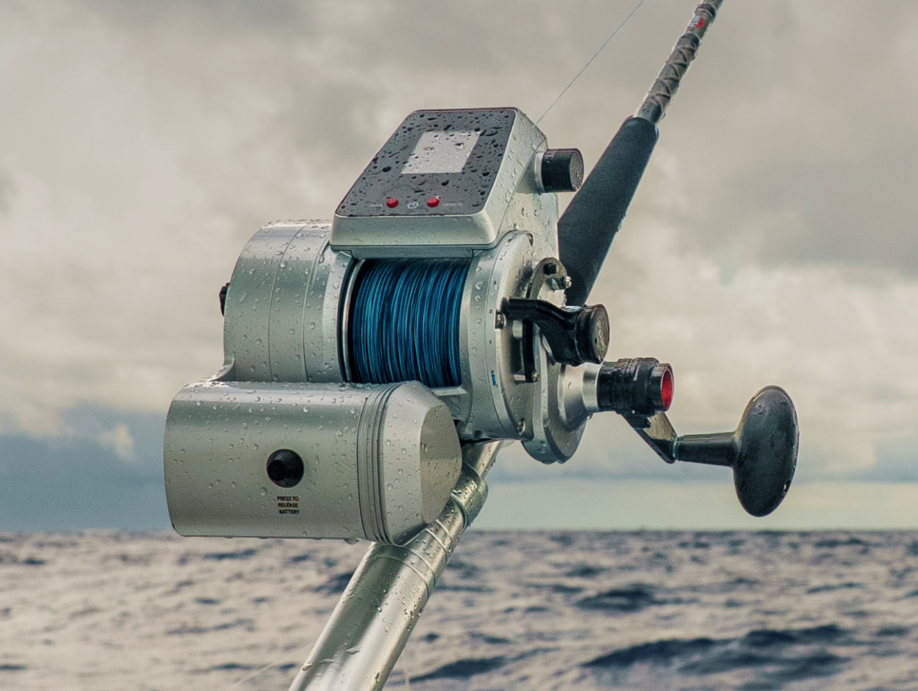 PENN Fathom Electric fishing reel on a boat with ocean and cloudy sky in the background