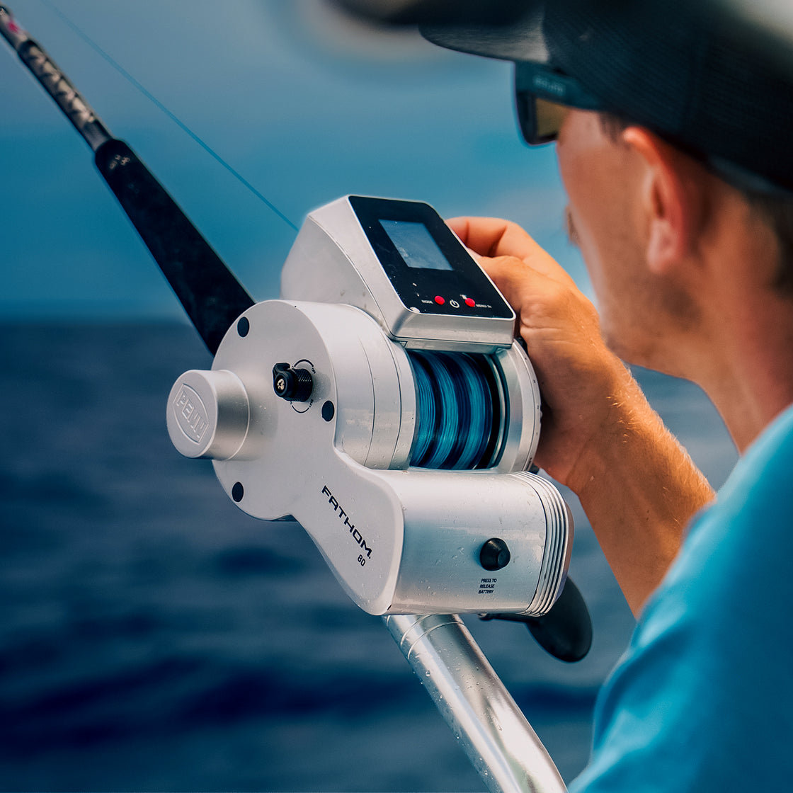 Person holding a fishing reel with digital display on a boat, water background