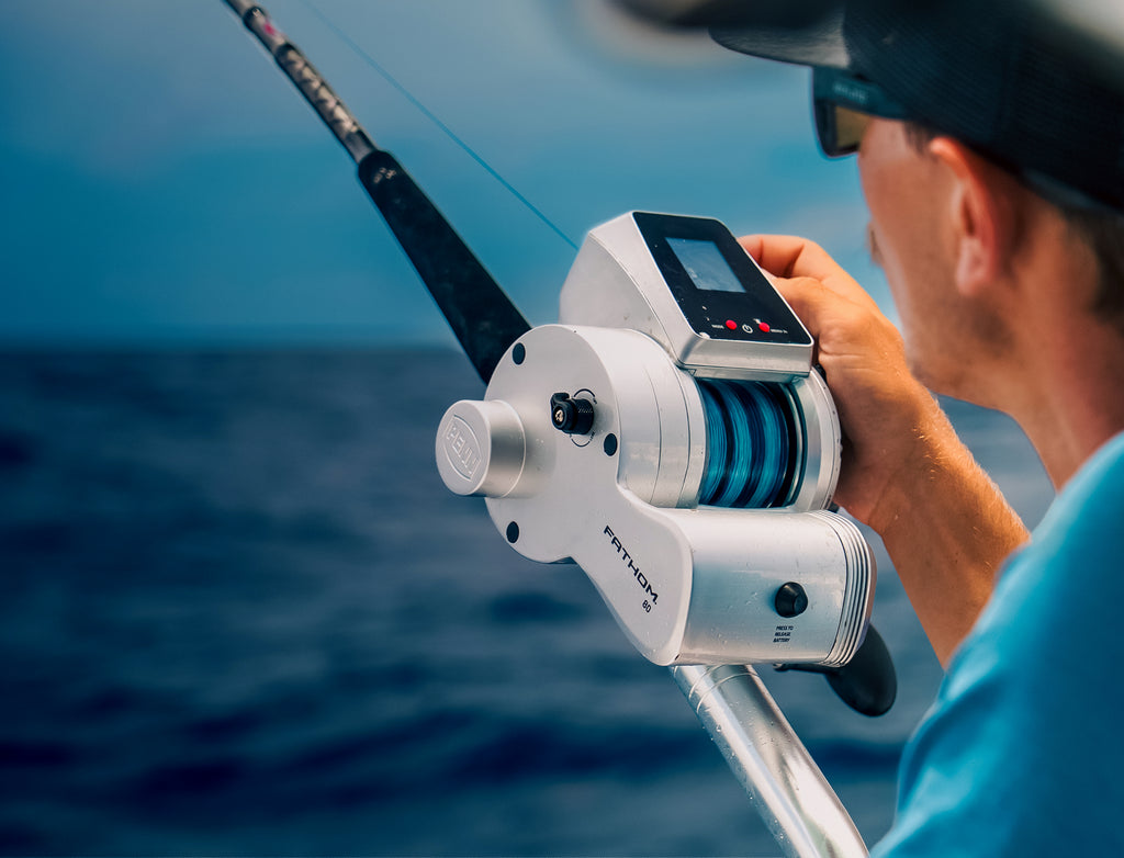 Person holding a fishing reel with a blurred ocean background