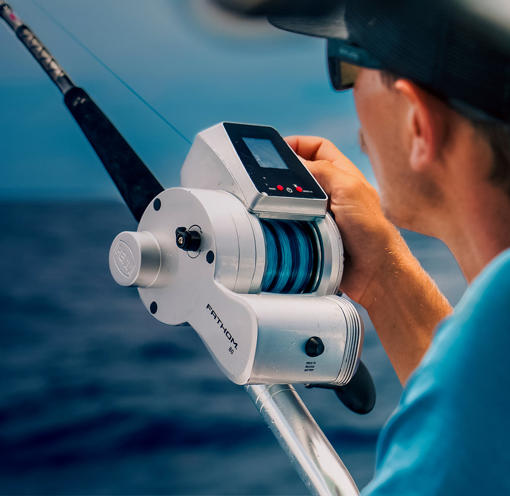 Person holding a fishing reel with digital display on a boat, water background