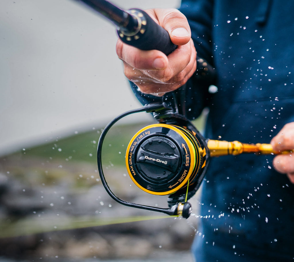Fishing rod with reel held by a person, water splashes in the foreground